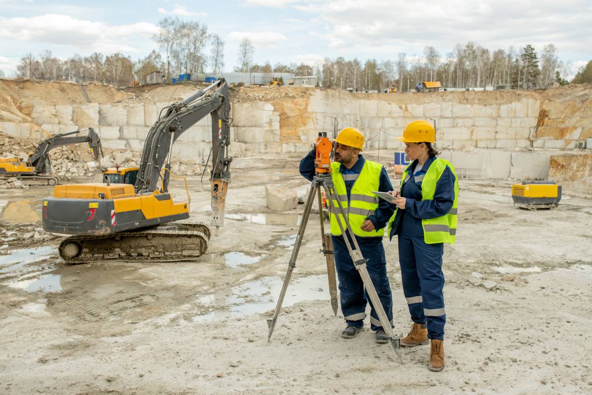 Male and female surveyors in uniform working on construction site