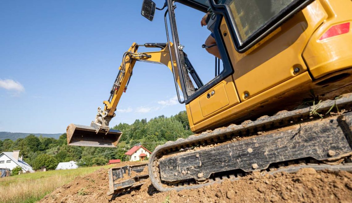 Mini excavator digging preparing ground under home garden